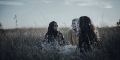 Black-and-white image of three women sitting in a field