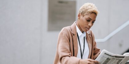 Black business woman focused on reading a news piece in the newspaper