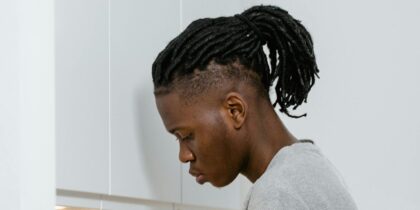 Side profile of a young black man with wearing grey shirt looking down.