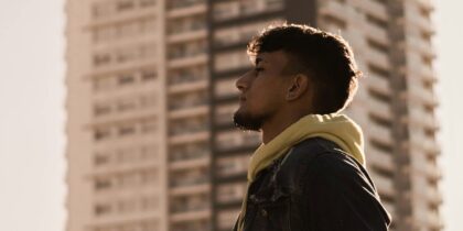 Young man in black jacket standing near high rise buildings during daytime