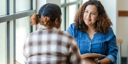 Two women in casual clothing having a discussion. One is an adviser, listening intently.