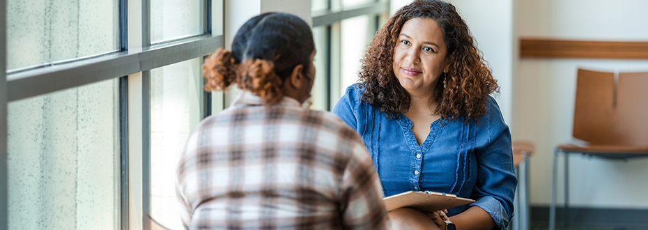 Two women in casual clothing having a discussion. One is an adviser, listening intently.