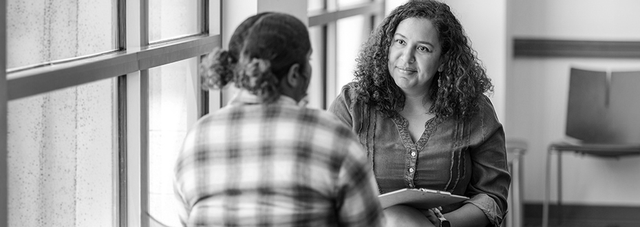 Two women in casual clothing having a discussion. One is a adviser, listening intently.