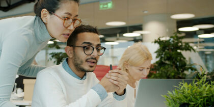 Two colleagues are talking while looking at laptop in shared office space