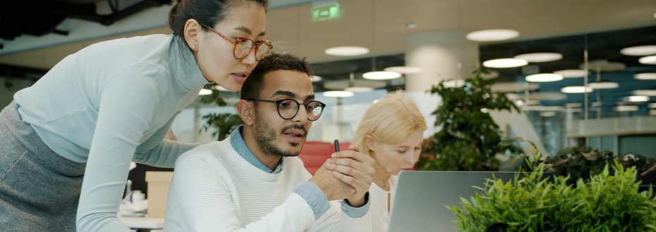 Two colleagues are talking while looking at laptop in shared office space