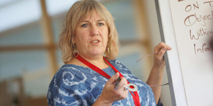 A woman stands at a flipchart, pen in hand