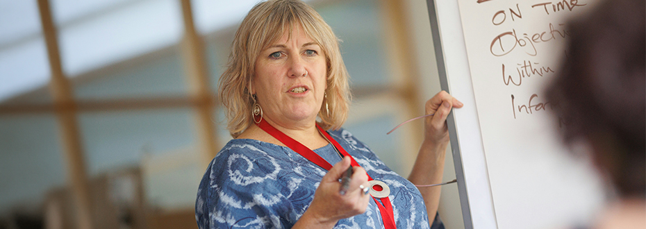 A woman stands at a flipchart, pen in hand