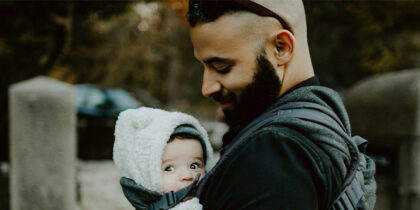 A man is holding a baby to his chest