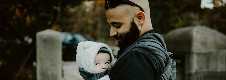A man is holding a baby to his chest