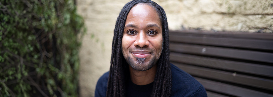 Photo of a young Black man, Jason Arday, smiling into the camera