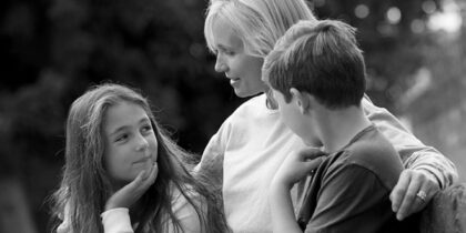 A mother is sitting outside with two children