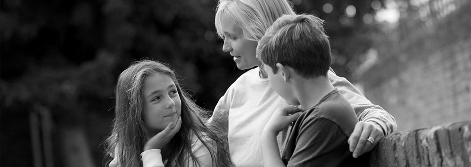 A mother is sitting outside with two children